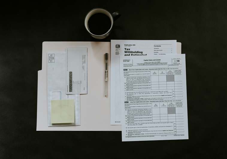 Friendly blogger writing at a desk with laptop, insurance documents, and home security checklist visible